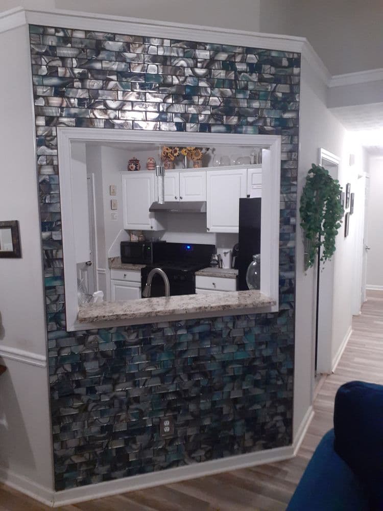 Modern kitchen view through decorative mosaic wall with open concept design.