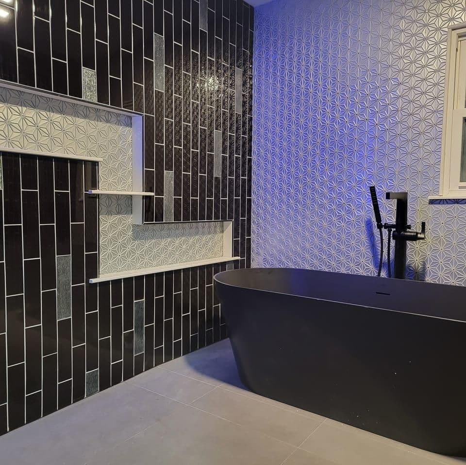 Modern bathroom design featuring black and blue patterned tiles and a freestanding bathtub.