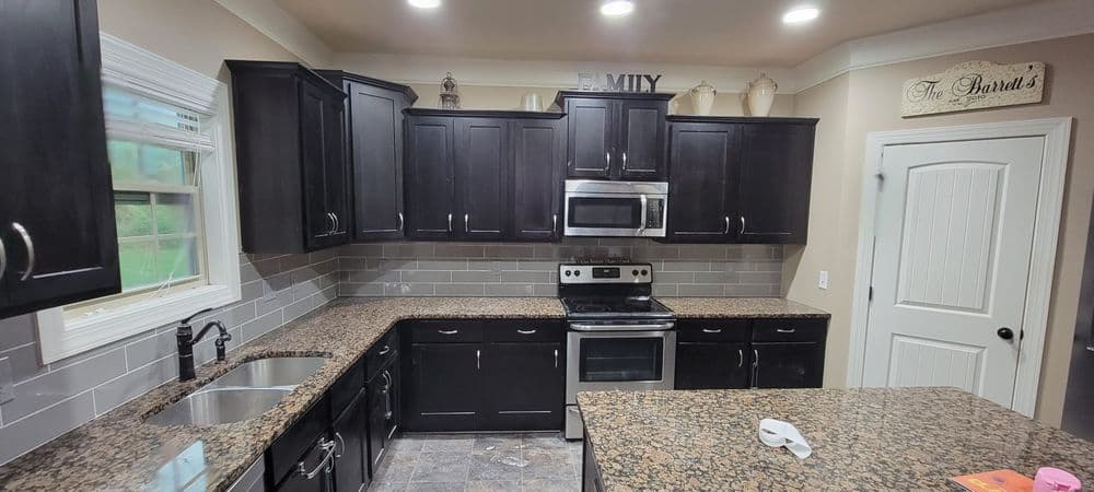 Modern kitchen with dark wood cabinets, granite countertops, and stainless steel appliances.
