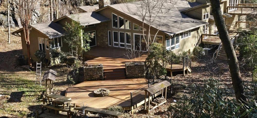 Modern cabin surrounded by nature with a wooden deck and outdoor seating area.