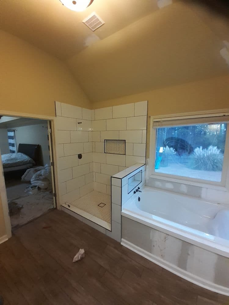 Modern bathroom renovation featuring a tiled shower and bathtub with natural light.