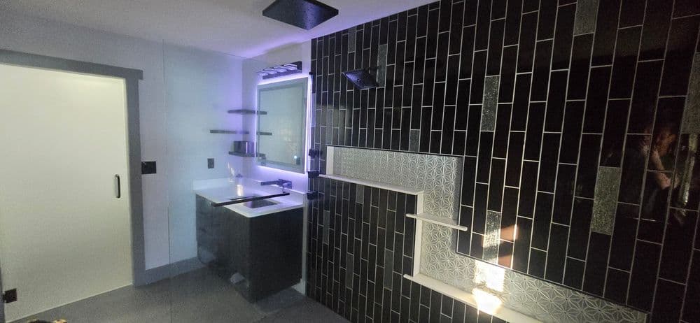 Modern bathroom design featuring black tile, sleek fixtures, and stylish lighting.