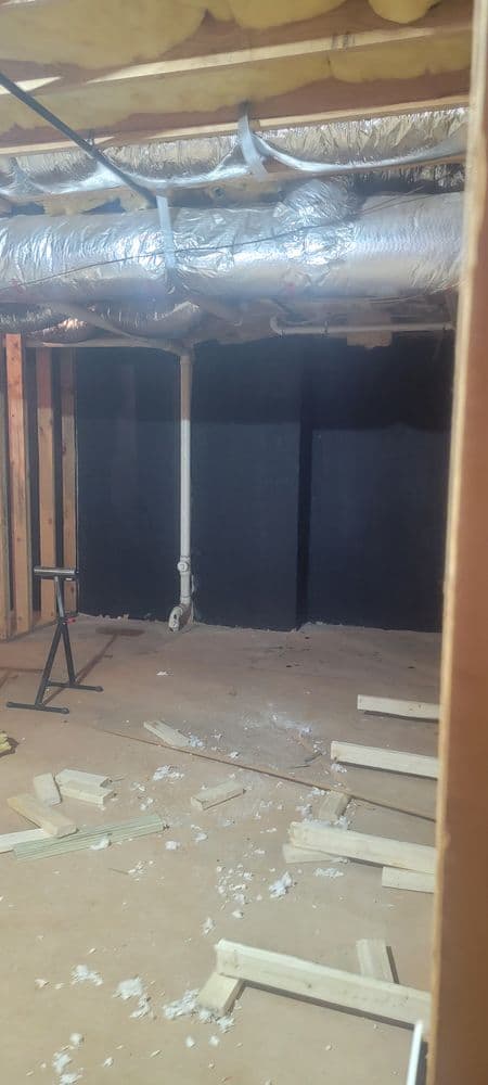 Empty basement under renovation with exposed ductwork and construction debris on the floor.