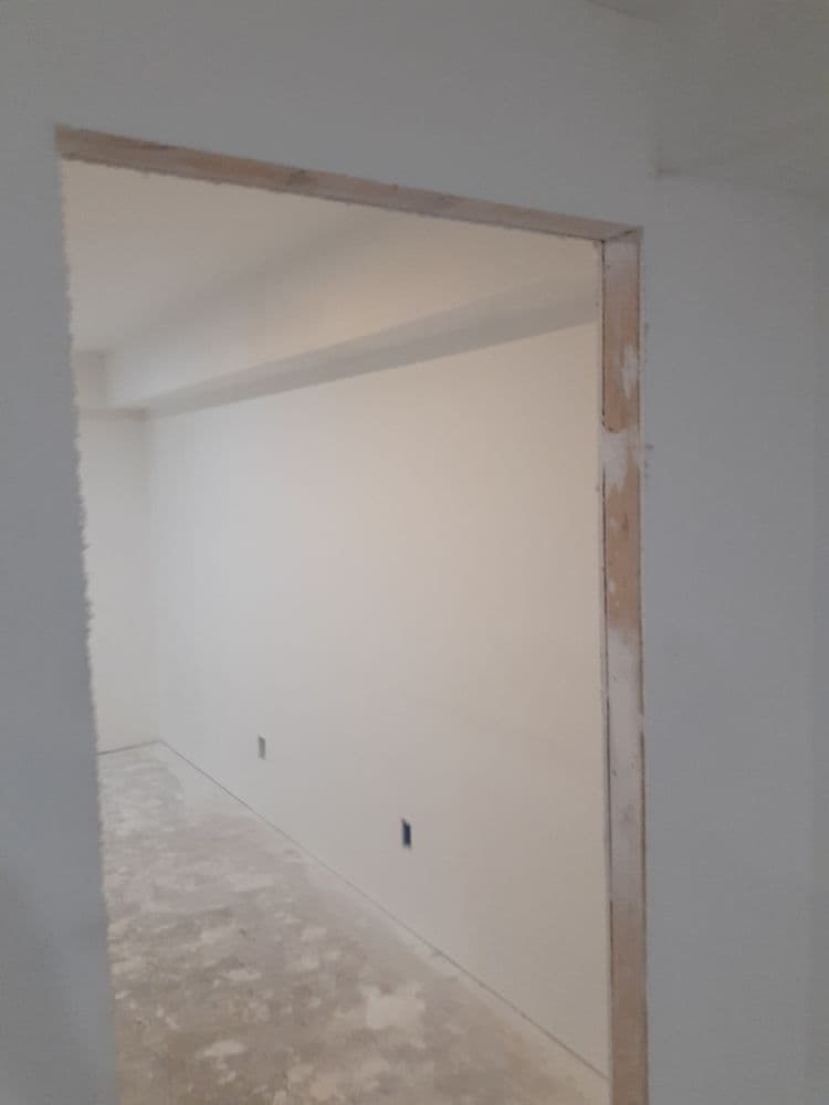 Interior view of a newly constructed room with drywall and unfinished floors.