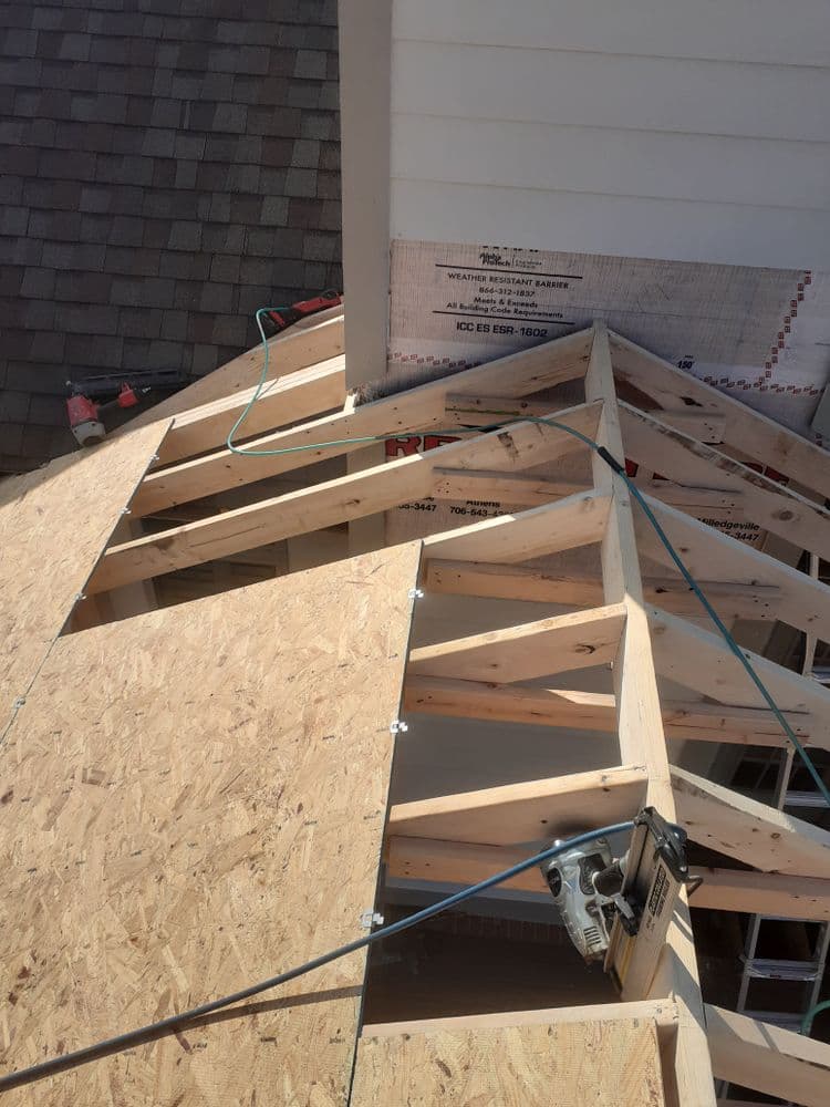 Roof construction with wooden trusses and a circular saw, showcasing framing details.