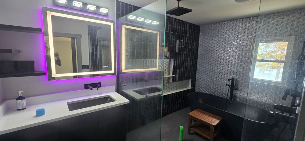Modern bathroom design with dual mirrors, sleek black tiles, and a freestanding bathtub.