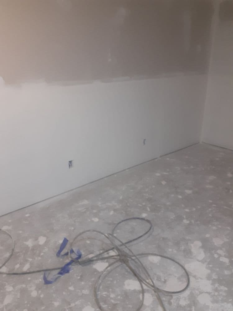 empty room with unpainted walls, uneven floor, and construction materials scattered around