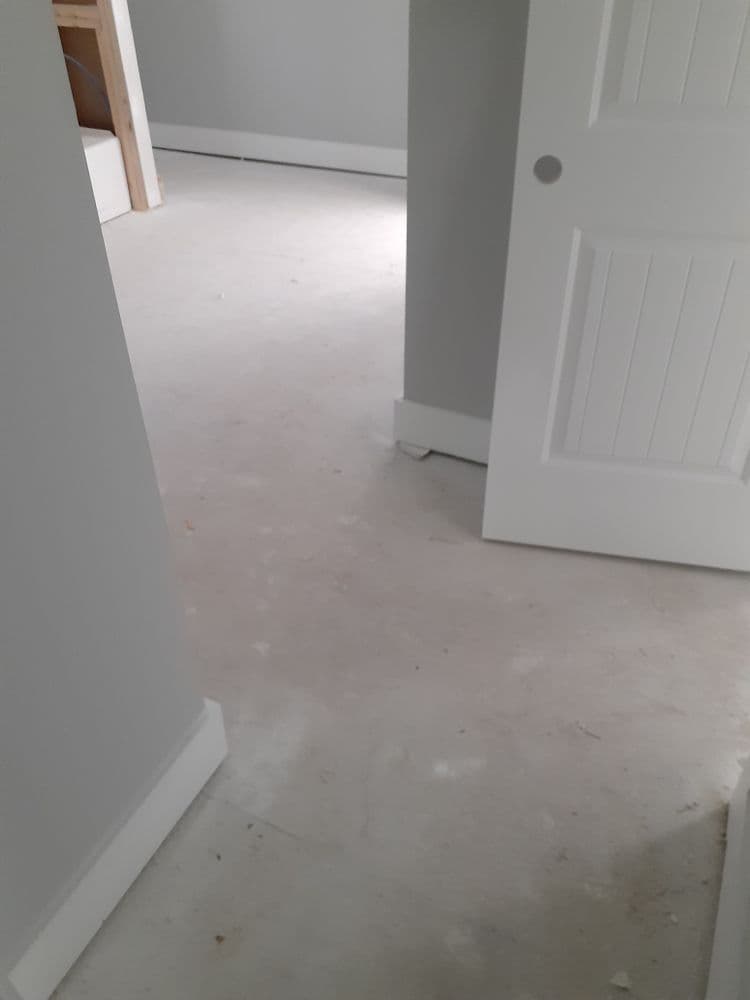 Interior view of a light gray room with smooth flooring and a partially open door.