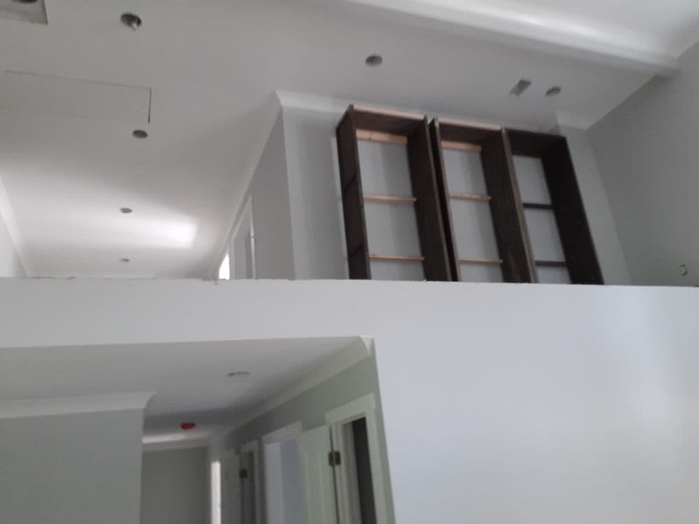Interior view of a modern home featuring open space, white walls, and empty wooden shelves.